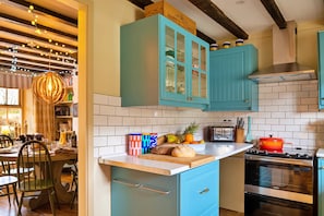 A kitchen with teal cabinets, a wooden island, a stove, and a dining area with chairs and a table. - Cottage in Dolwyddelan Near Snowdon (Dolwyddelan)