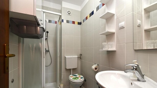 Ein Badezimmer mit Dusche, Toilette, Waschbecken und Spiegel.