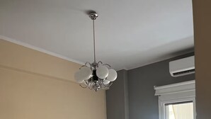 Un dormitorio con cama, una silla, ventilador de techo y ventana con persianas.