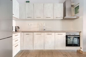 A modern kitchen with light-colored cabinets, a stainless steel refrigerator, a built-in oven, and a wooden countertop. - Luxury Serenity-Cozy Stay by the Sea and Marina (Pireas)