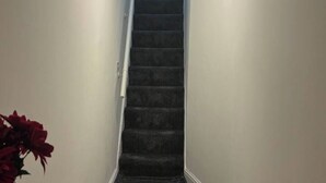Un escalier étroit, recouvert de moquette, menant à l’étage supérieur.
