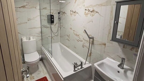 Ein modernes Badezimmer mit einer Duschkabine, einer weißen Toilette, einer Badewanne und einem Waschbecken mit Spiegel darüber.