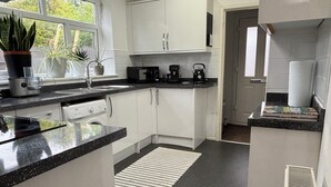 A modern kitchen with white cabinets, a black countertop, and a window with plants.