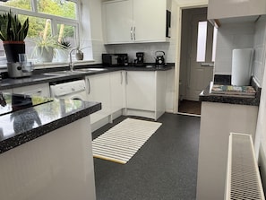 A modern kitchen with white cabinets, a black countertop, and a window with plants.