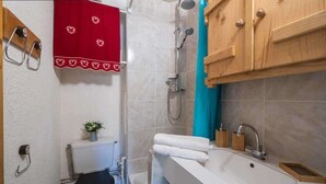 Et badeværelse med toilet, bruser, vask og træskabe.