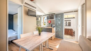 A compact living space with a kitchenette, a dining area with a wooden table, and a small seating area.