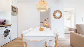 Una cocina moderna con microondas, lavadora y comedor con mesa y sillas.