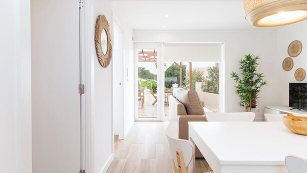 Una cocina moderna con encimera blanca, un comedor con mesa blanca y vistas al patio exterior.