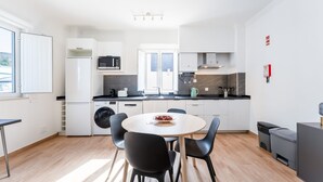 A modern kitchen with a dining area, including a round table with chairs, a washing machine, a microwave, and a coffee maker. - Modern Retreat in Castro Marim by LovelyStay (Castro Marim)