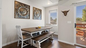 Un comedor con una mesa y sillas de madera, dos adornos en la pared, una cabeza de toro montada y un ventanal corredizo que da a una terraza exterior.