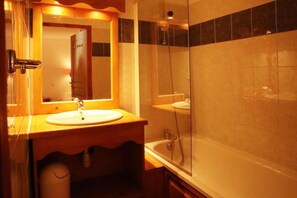 A bathroom with a wooden vanity, a sink, a mirror, and a glass-enclosed shower.