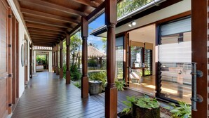 A covered wooden walkway with columns, leading to a glass door entrance.