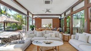 A spacious living area with a large L-shaped sofa, a round coffee table, and a dining area with a table set for four.