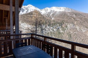 Una cabaña de madera con un balcón que domina montañas nevadas.