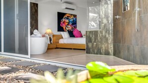 A modern bedroom with a bed, a bedside table with a lamp, and a colorful abstract painting on the wall.