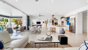 A modern living room with a sofa, coffee table, and a dining area with chairs.