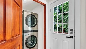 A laundry room with two stacked washing machines and a white door with a window. - Lakefront Retreat for 6 with Stunning Views, Sauna (Snohomish)