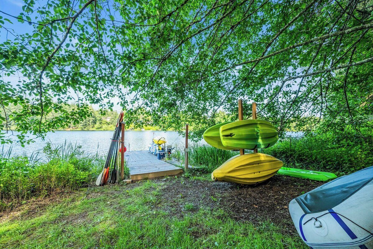 A lakeside camping area with kayaks and a dock.