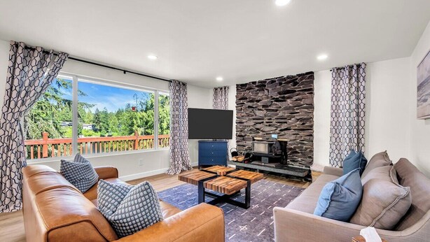 A living room with a sofa, coffee table, and a flat-screen TV. - Lakefront Retreat for 6 with Stunning Views, Sauna (Snohomish)