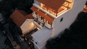 Un edificio de varios pisos con fachada blanca, varios balcones y techo de tejas rojas.