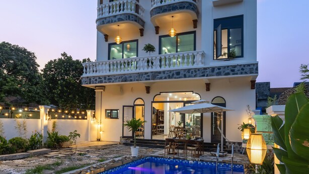 Un edificio de varios pisos con piscina, balcones y zona de estar exterior.