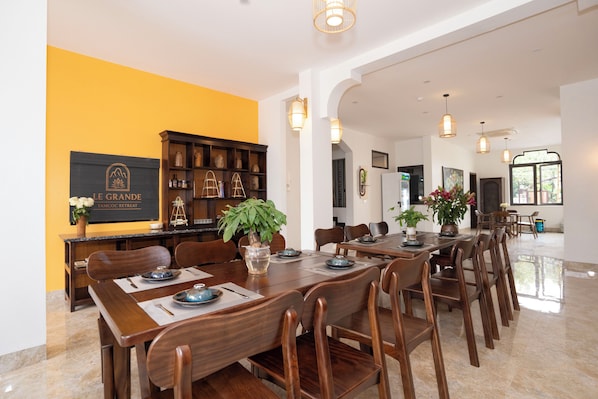 A dining area with a long wooden table, chairs, and a buffet counter with a potted plant.