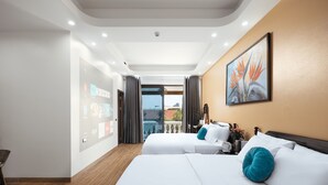 Habitación de hotel con dos camas, una pantalla digital que muestra información de la habitación, vistas al exterior y un cuadro en la pared.