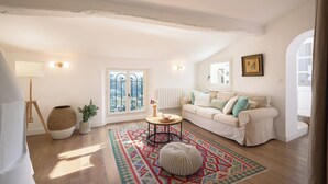 Una sala de estar acogedora con un sofá blanco, un tapete estampado y piso de madera.