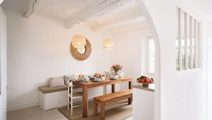 Un rincón comedor acogedor con una mesa de madera dispuesta para el desayuno, un banco y una lámpara fijada a la pared.