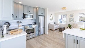 Une cuisine moderne avec des meubles bleu clair, des appareils en acier inoxydable et un plan de travail blanc.