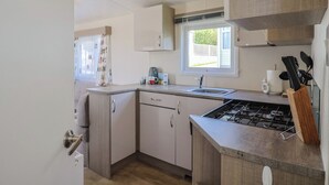A compact kitchen with a gas stove, a sink, and a window providing natural light. - Willow's Leap (Lyme Regis)