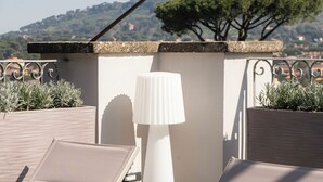 A rooftop terrace with two lounge chairs, a white lamp, and a view of a tree and hills. - Villa Madre Suites e Private Spa (Grottaferrata)