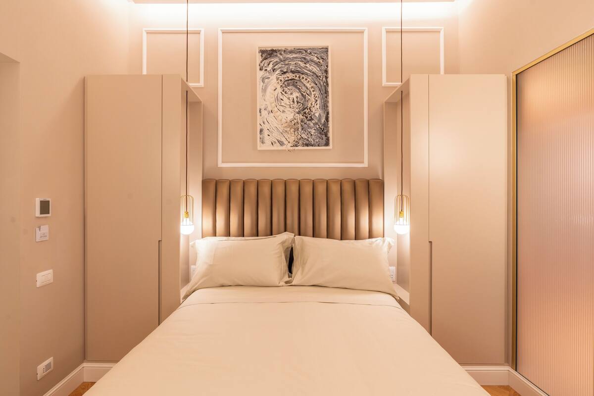 Une chambre à coucher avec un lit, une tête de lit, des lampes de chevet et un tableau au mur.