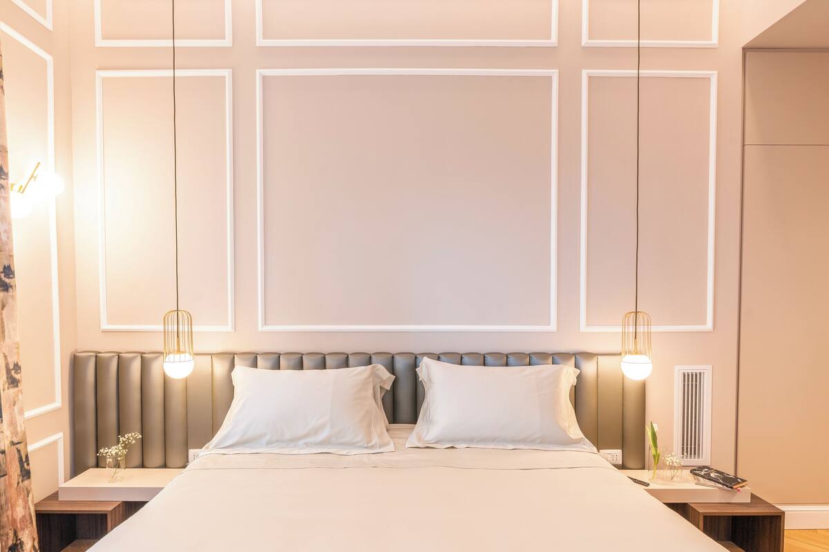 Une chambre à coucher bien aménagée, avec un grand lit, deux tables de chevet et une tête de lit dotée d’un éclairage intégré.