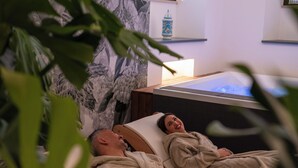Une salle de spa équipée d’une table de massage, d’une fresque murale et d’un petit objet décoratif posé sur une étagère.