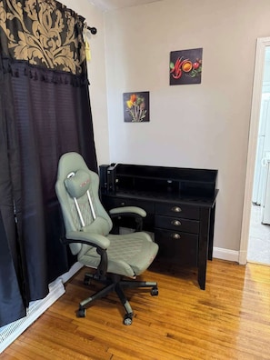 A room with a green office chair, a black desk, and two framed artworks on the wall. - 3BR King Beds | 85” TV | 4min to A&T & Downtown (Greensboro)
