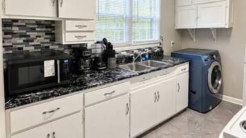 A modern kitchen with white cabinets, a black countertop, and a built-in washing machine.