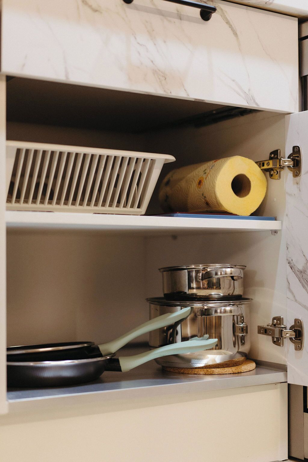 Un armario de cocina con encimera de mármol, un extractor blanco y un rollo de toallas de papel.