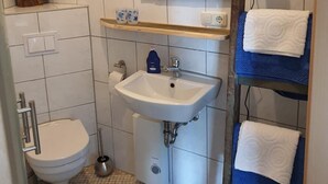 Un baño con lavamanos blanco, inodoro, espejo y toallero.