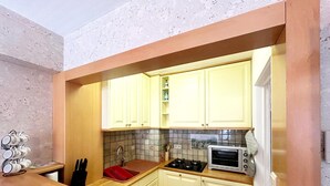 A compact kitchen with white cabinets, a red sink, a stove, and a microwave. - Apartment 700 Meters From Baldus Beach (Koksijde)
