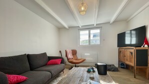 A living room with a sofa, a coffee table, a television, and a window. - Ty Camelia-Draps included-4p-Wifi-Enclosed garden (QUIBERON)