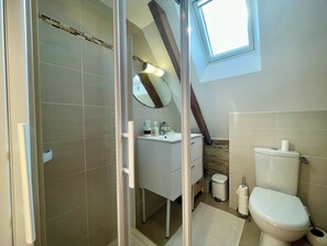 Une salle de bain équipée d’une douche, de toilettes, d’un lavabo et d’un miroir.