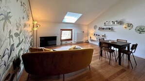 A living room with a sofa, TV, and dining area with chairs and a table. - Historia Suite Bellagio (Bellagio)