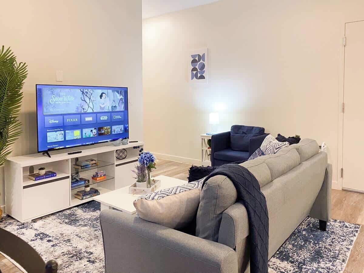 A living room with a flat-screen TV, a sofa, a coffee table, and a bookshelf.