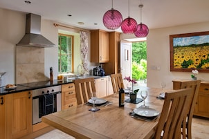 A modern kitchen with wooden cabinets, a large island, and a dining area with a wooden table and chairs.