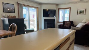 A cozy living room with a fireplace, a television, and a dining area with a table and chairs. - True Ski In/Out  2 bedroom condo (Jay)