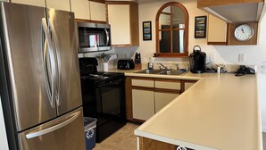 A modern kitchen with stainless steel appliances, wooden cabinets, a microwave, a toaster, and a sink. - True Ski In/Out  2 bedroom condo (Jay)