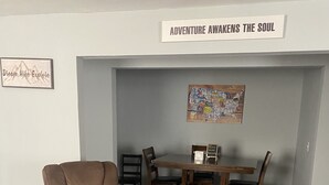 A room with a brown recliner chair, a wooden dining table with chairs, and a wall sign that reads "ADVENTURE AWAKENS THE SOUL". - Welcome to Gods country lodging located in the heart of Hatfield and mcoy trails (Delbarton)