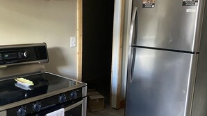 A kitchen with a stainless steel refrigerator, an oven, and a stove. There are wooden cabinets above the counter. - Welcome to Gods country lodging located in the heart of Hatfield and mcoy trails (Delbarton)