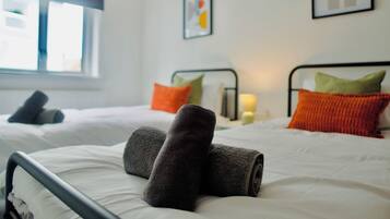 A hotel room with two beds, each with white bedding and colorful pillows.